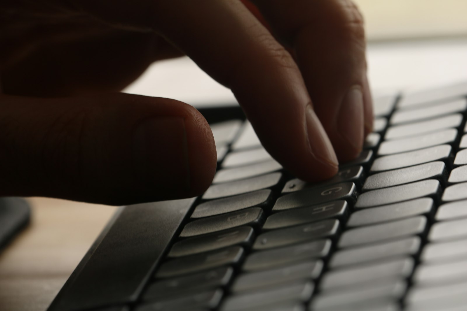 Mãos digitando em teclado escuro
